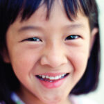 Little girl with dark hair smiles with a healthy smile in San Antonio, TX