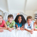 Group of kids on a bed smile with dental sealants in San Antonio, TX