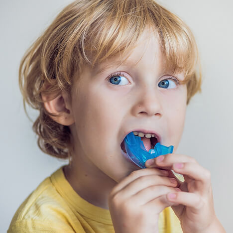 young boy holding his mouthguard